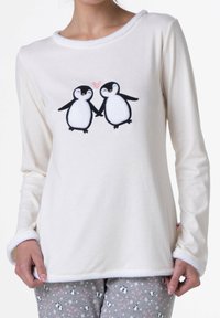 Maglia a maniche lunghe color crema con scollo rotondo, caratterizzata da un ricamo che raffigura due pinguini che si tengono per la pinna, circondati da un cuore.