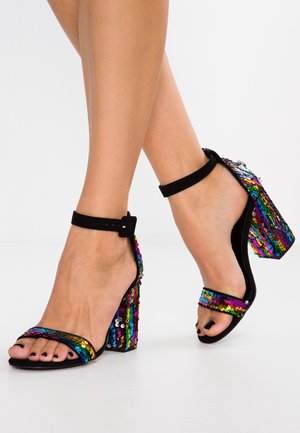 Sandały na wysokim obcasie z czarnym paskiem i błyszczącym, wielokolorowym obcasem pokrytym cekinami. Szczegóły z teksturowanej tkaniny i zapięcie na kostce.
