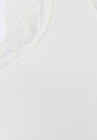 Valkoinen kangas, jossa on sileä pinta ja pitsiyksityiskohtia kaula-aukolla. Mallissa on saumaton rakenne ja hillitty ribbi. 