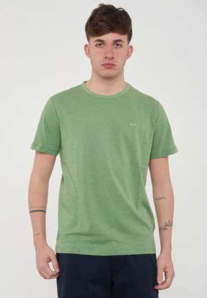 T-shirt verde a maniche corte realizzato in morbido cotone con collo a giro. Presenta un piccolo logo bianco sul petto. Il tessuto ha una finitura liscia e leggermente strutturata.