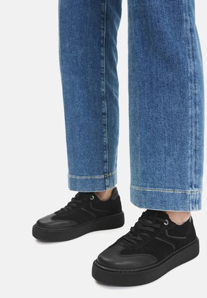 Sneakers nere con una combinazione di pelle liscia e suede. Design con lacci, collarino imbottito e suola piatta testurizzata. Indossate con jeans di denim blu.