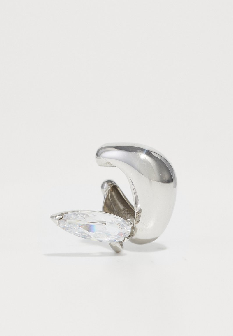 Hopea metalliklipsi, jossa on sileä, kaareva muoto ja kirkas, marquise-leikkauksella varustettu kristallikoriste. Kiiltävä pinta, minimalistiinen muotoilu.