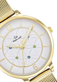 Montre à bracelet en mailles dorées avec un cadran blanc, motif floral et index horaires dorés. Présente des accents colorés en pierres précieuses bleues et vertes.