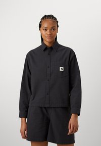 Svart rutigt skjorta med knappar och ficka samt logotyp patch, med avslappnad passform och långa ärmar, parat med matchande shorts.