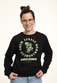 Sudadera negra con gráficos que presentan a un astronauta de dibujos animados patinando. El texto incluye "Santa Monica Space Cruisers" y "vida sin límites."