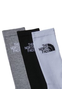 Tres pares de calcetines: gris, negro y blanco. Textura acanalada con el logo de "The North Face" bordado en blanco en cada calcetín.