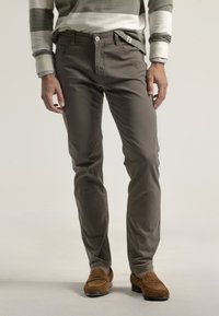 Pantalones de algodón grises con corte slim, que incluyen bolsillos frontales, cierre de botón y se estilizan con mocasines de ante marrón.