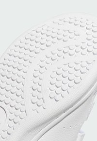 Sole di sneaker bianca con superficie tessurizzata caratterizzata da motivi circolari e bordi lisci, realizzata in gomma con dettagli leggermente in rilievo.