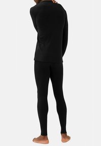 Schwarzes Thermo-Top und Leggings in figurbetontem Design mit gerippter Struktur. Das Material ist glatt, mit Ärmeln in voller Länge und knöchellang.