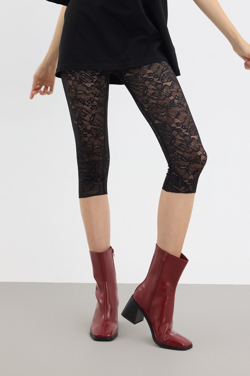 Sorte blonder leggings med blomstermønster, kortere lengde, parret med røde ankelstøvler med firkantet tå og chunky hæl.