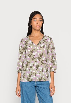 Blusa floral em verde-oliva com flores roxas e brancas, decote em V, mangas 3/4 e fecho frontal com botões. Tecido leve com uma textura suave.