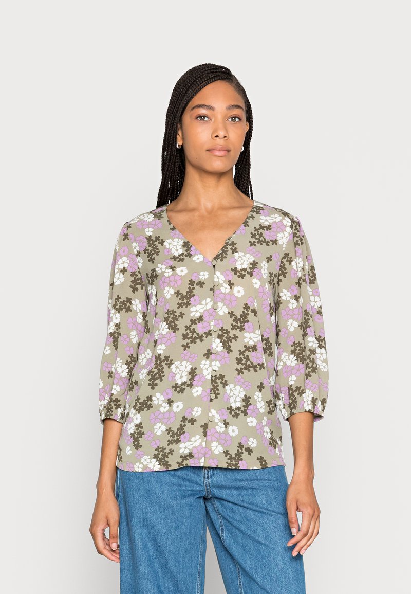 Blusa floral em verde-oliva com flores roxas e brancas, decote em V, mangas 3/4 e fecho frontal com botões. Tecido leve com uma textura suave.