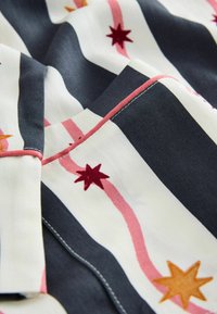 Gemusterter Stoff mit Streifen in Marineblau, Weiß und Pink, verziert mit bunten Sternmotiven in Rot, Orange und Gelb. Glatte Textur und gestickte Kanten.