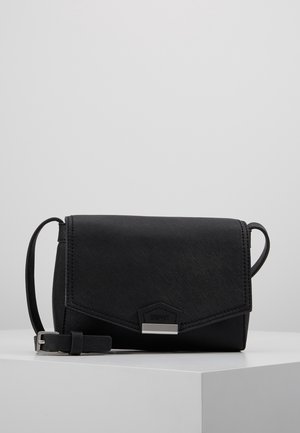 Bolso bandolera negro con solapa texturizada, cierre plateado, correa ajustable y logo de la marca sutil sobre una superficie blanca.