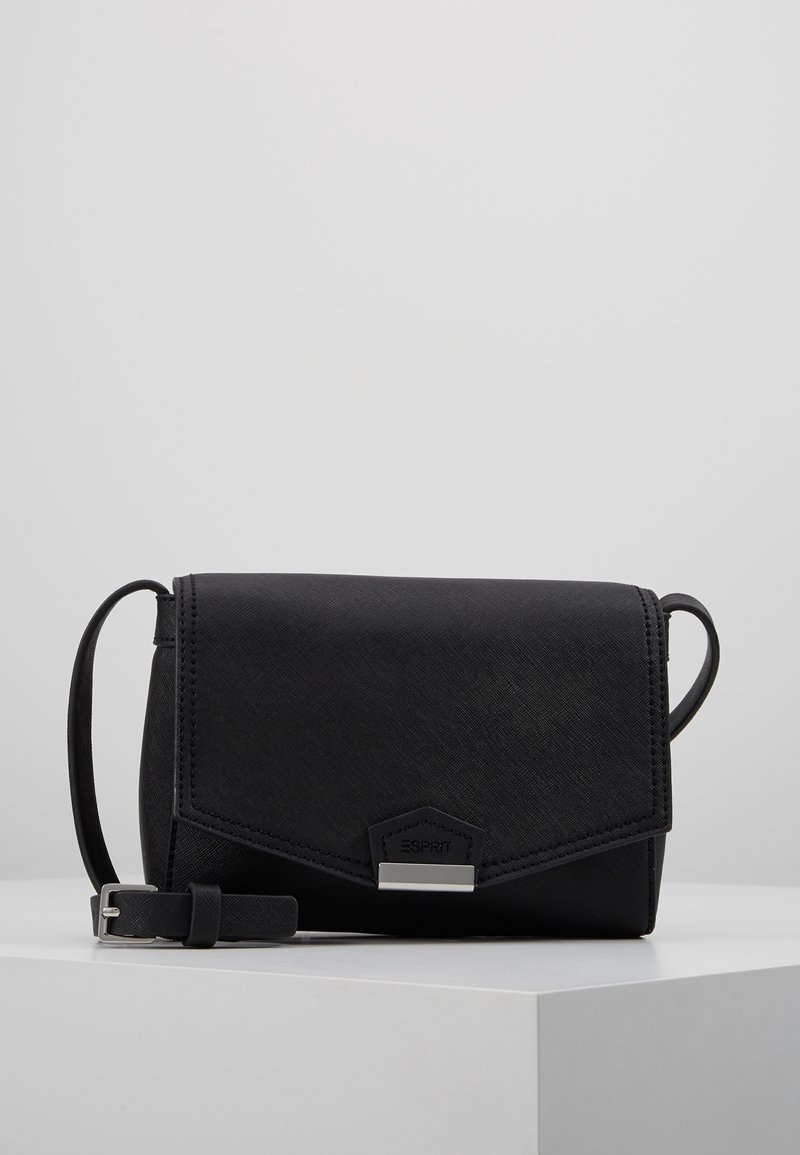 Sac bandoulière noir avec rabat texturé, fermoir argenté, sangle réglable et logo discret de la marque sur une surface blanche.