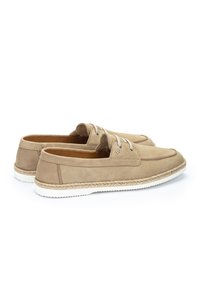 Zapatos náuticos de ante beige con suelas de goma blanca, detalles de cordones y un acento de yute trenzado alrededor de la suela. Diseñados para uso casual.
