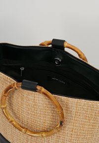 Borsa a tracolla di paglia intrecciata di colore tan con manici rotondi in bambù, interno nero e tasca con zip. Presenta l'etichetta del marchio "NEW LOOK" all'interno.