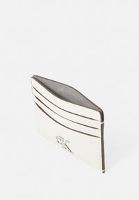 Tarjetero de cuero blanco con acentos marrones, que cuenta con múltiples ranuras para tarjetas y una superficie texturizada. Detalle del logo en plata en la parte frontal.