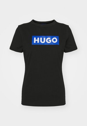 T-shirt noir à manches courtes en coton, avec un grand graphique rectangulaire bleu comportant le mot "HUGO" en lettres blanches épaisses.