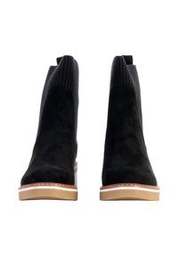 Bottines en daim noir avec des tiges en tricot côtelé et des semelles en caoutchouc beige. Présentent des détails de couture autour du bord de la semelle.