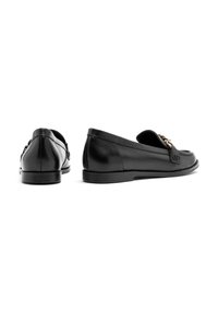 Black leather loafers with a sleek design, flat rubber soles, and a decorative metal chain accent on the front. Smooth texture.
