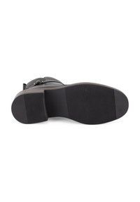 Schwarze Leder-Stiefelette mit einer strukturierten Gummisohle, ausgestattet mit einer abgerundeten Spitze und einem vertikalen Streifenmuster auf dem Obermaterial.