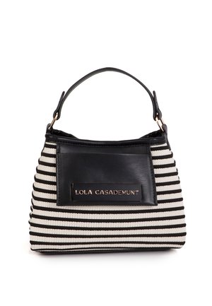 Bolso de tela con rayas blancas y negras, con un detalle y asa de cuero negro. Cuenta con una placa metálica con el logotipo en el frente.