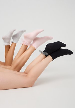 Calzini alla caviglia nei colori grigio, rosa e nero, con bordo arricciato trasparente e dettaglio a fiocco. Texture liscia e design aderente.