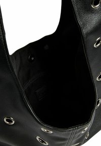 Zwarte totebag met grote openingen, textuur synthetisch materiaal, zilveren hardware accenten en een zwart stoffen interieur met een ritsvak.