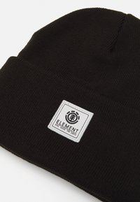 Black knitted beanie with a folded cuff. Features a square white patch with a black logo text "ELEMENT" and graphic elements below.