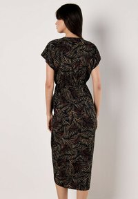 Robe noire avec un motif feuillu dans des tons dorés, rouges et verts. Manches courtes, taille cintrée et design jusqu'aux genoux. Texture lisse.
