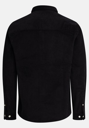 Camisa de pana negra con cuello clásico, mangas largas y puños abotonados. La tela texturada presenta costillas verticales, lo que añade profundidad.