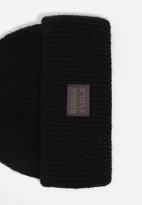 Gorro de lana negro con textura acanalada y una etiqueta de tela rectangular que presenta "BIMBA Y LOLA" en letras grises.