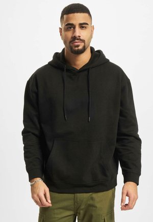 Sweat à capuche noir en tissu doux, doté d'une poche kangourou à l'avant et de cordons de serrage. Deuxième coupe décontractée.