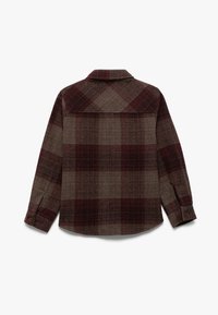 Rood en bruin geruite flanellen shirt met een spitse kraag, knoopmanchetten en een rechte rugnaad. Kenmerkt zich door een gestructureerde wolmixstof.