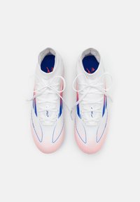 Ett par vita sportskor med blå och rosa detaljer, snörda och sedda ovanifrån mot en enkel vit bakgrund.