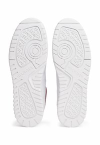 Witte sneakersole met een textuurpatroon voor grip; bevat cirkelvormige details en "HILFIGER" branding op één van de zolen; van glad, duurzaam materiaal.