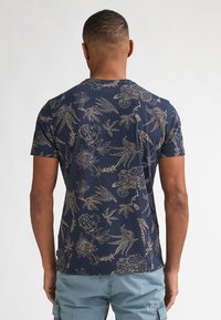 Marineblauw T-shirt met korte mouwen en een goudkleurig bloemen- en vogelpatroon. Zachte stof, ronde hals en een ontspannen pasvorm.