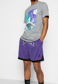 Gray cotton t-shirt with a colorful basketball graphic on the front, paired with purple mesh shorts featuring "JORDAN" lettering and a logo.