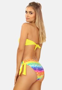 Zestaw bikini składający się z żółtego topu bandeau z zapięciem na sznurek oraz spodni w wielokolorowym wzorze gradientowych fal z wiązaniem po bokach.