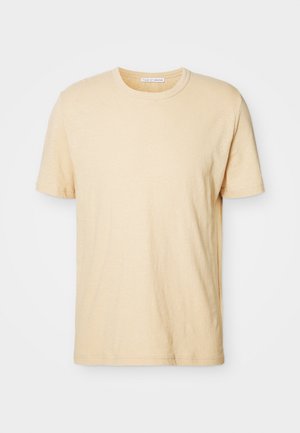 T-shirt de mangas curtas, cor creme, com gola redonda, feito de tecido suave, apresentando um design simples e sem adornos.