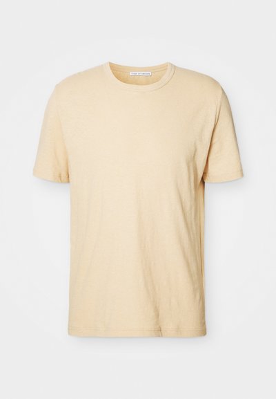 Camiseta de manga corta color crema con cuello redondo, hecha de una tela suave, con un diseño simple y sin adornos.