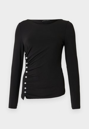 Haut noir à manches longues avec un col rond, doté de fronces latérales et d'accents de boutons blancs sur le côté gauche. Texture de tissu lisse.