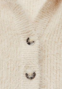Hellbeige gestrickte Strickjacke mit weicher Textur, offenem Gewebe und zwei runden, gemusterten Knöpfen an der vorderen Blende.