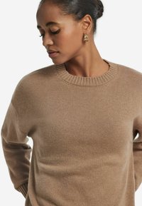 Beiger Pullover aus weich gestricktem Material, mit Rundhalsausschnitt und gerippten Bündchen. Glatte Textur, lässige Passform.