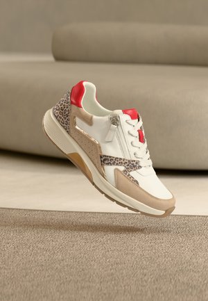Fehér bőrfelső részű, bézs díszítésekkel és leopárdmintás szekcióval ellátott sportcipő. Piros sarokdísz és texturált talp. Könnyű kialakítás.