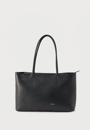 Svarte skinnveske med perforert geometrisk mønster og doble håndtak, liten Calvin Klein-logo midt foran.