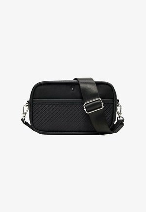 Črna pravokotna torbica čez ramo s potiskanim sprednjim delom, širokim nastavljivim naramnim trakom in srebrnimi kovinskimi zaponkami na belem ozadju.