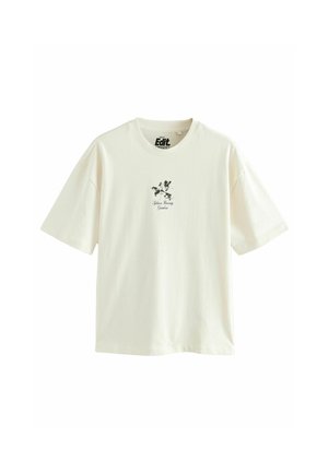 Bombažna majica v kremni barvi s kratkimi rokavi in okroglim izrezom. Na sredini je črni cvetlični grafični vzorec.