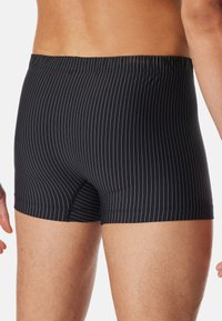 Boxer briefs neri con sottili strisce bianche verticali, elastico in vita e vestibilità aderente, realizzati in morbido tessuto elasticizzato.